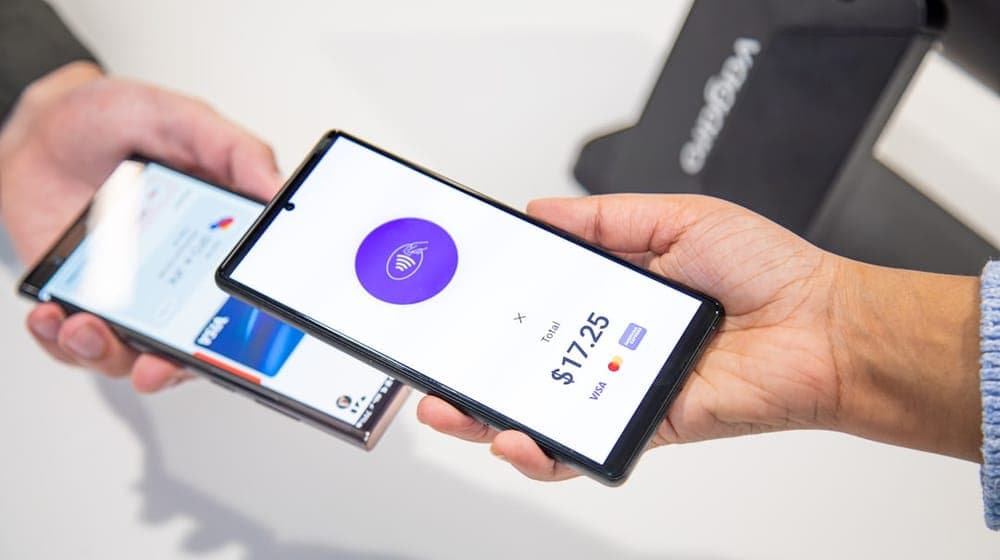 A business owner is checking out a customer using Android-to-Android tap-to-pay at the front desk. A Vagaro PayPro is in the background of this transaction.