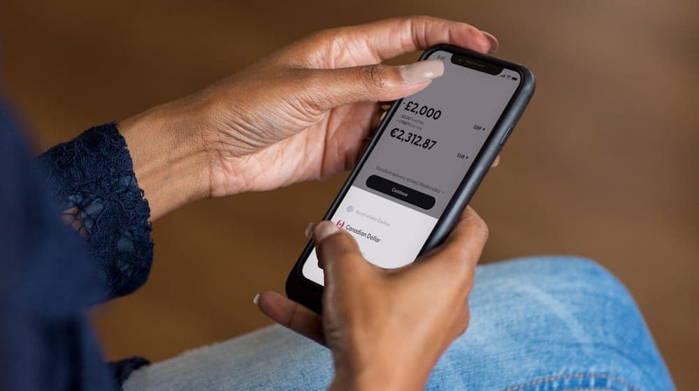 Hands holding a smartphone using a banking app to transfer money.