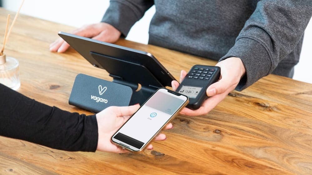 A business owner is checking out a customer using Apple Pay with the Vagaro contactless card payment system. The sleek and modern payment process introduces a touch of convenience, enhancing the overall checkout experience.